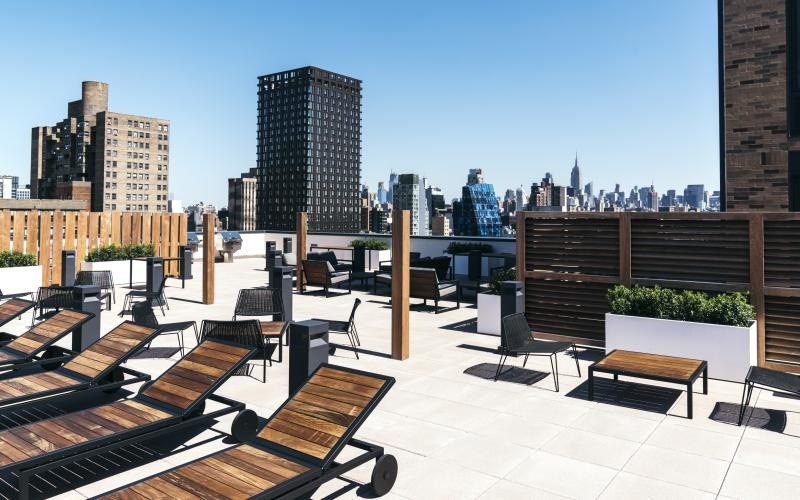 a patio with tables and chairs and a city skyline in the background